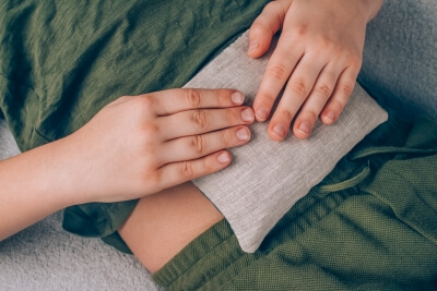 Körnerkissen für die Schmerztherapie Ein Junge benutzt ein Körnerkissen am Bauch