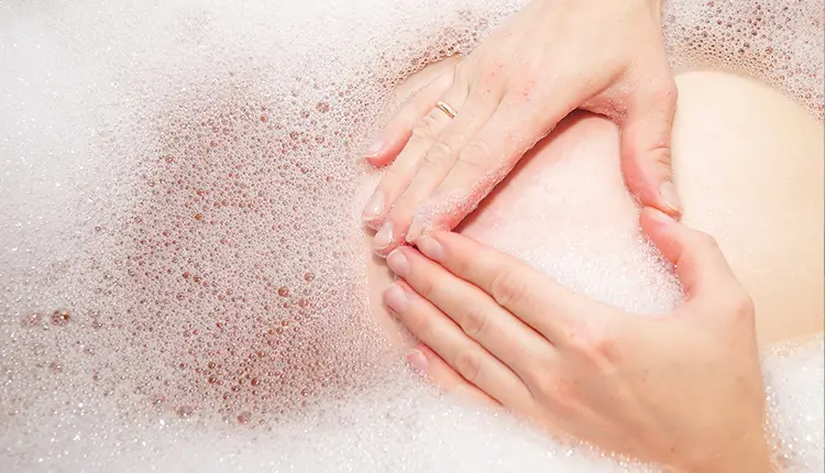 Schwangere in einer Badewanne. Ein eingelassenes Bad als Alternative zur Wärmflasche bei Schwangerschaft.