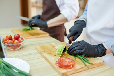 Schwarze, puderfreie Einmalhandschuhe in der Gastronomie Puderfreie Einmalhandschuhe werden zum Gemüse schneiden verwendet