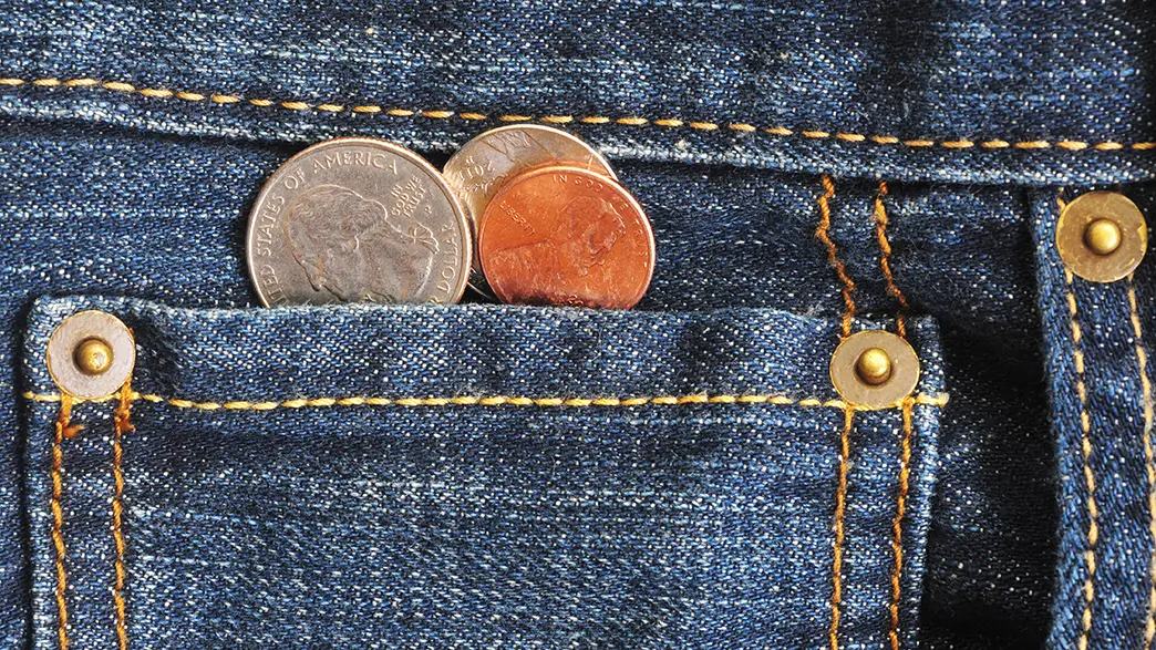 Jeansknöpfe und Münzen enthalten oft Nickel Eine Jeans mit nickelhaltigen Knöpfen und einige alte Münzen
