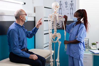 Ärztin klärt einen patienten mit einem Anatomie Skelett auf