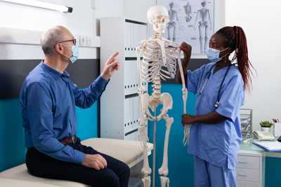 Patientenaufklärung mit einem Anatomie Skelett Ärztin klärt einen patienten mit einem Anatomie Skelett auf