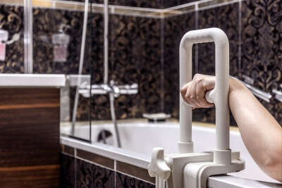 Handlauf für Behinderte und ältere Menschen Hand hält sich an Haltegriff für eine Badewanne fest