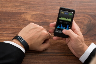 Aktivitätsdaten können über ein Smartphone ausgewertet werden. Mann mit Aktivitätssensor prüft Fitness-Statistiken auf dem Handy.