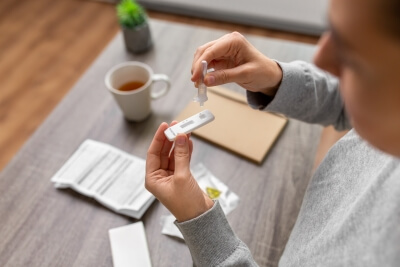 Point-of-Care-Test zu Hause Eine Frau macht einen medizinischen Schnelltest zu Hause am Tisch