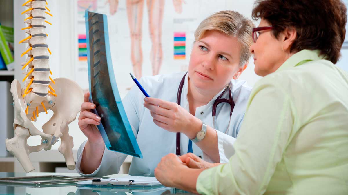 Eine Ärztin erklärt ihrer Patientin Röntgenaufnahmen der Wirbelsäule