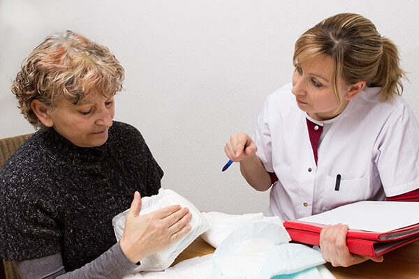 Eine Pflegerin bespricht Inkontinenzslips mit einer Patientin