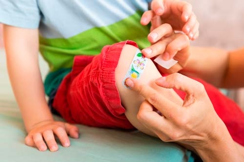 Pflaster für Kids Buntes Kinderpflaster wird auf Kinderknie aufgeklebt