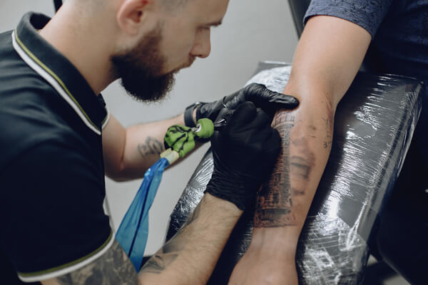 Nitril Handschuhe im Tattoostudio Tätowierer trägt schwarze Nitrilhandschuhe