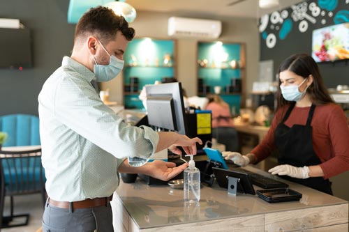 Hautdesinfektionsmittel im Alltag Mann benutzt Hautdesinfektionsmittel im Café