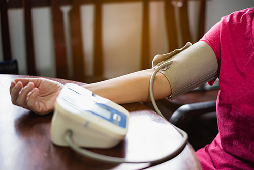 Eine Frau misst mit einer Blutdruckmanschette ihren Blutdruck