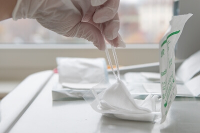 Ein Arzt holt mit einer Pinzette eine sterile Kompresse aus der Verpackung