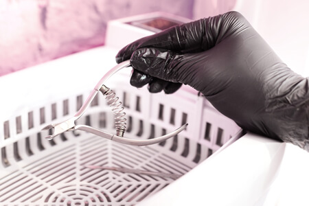 Desinfektionsmittel für die Instrumentendesinfektion Eine medizinische Zange wird mit Desinfektionsmittel in einer Desinfektionswanne sterilisiert